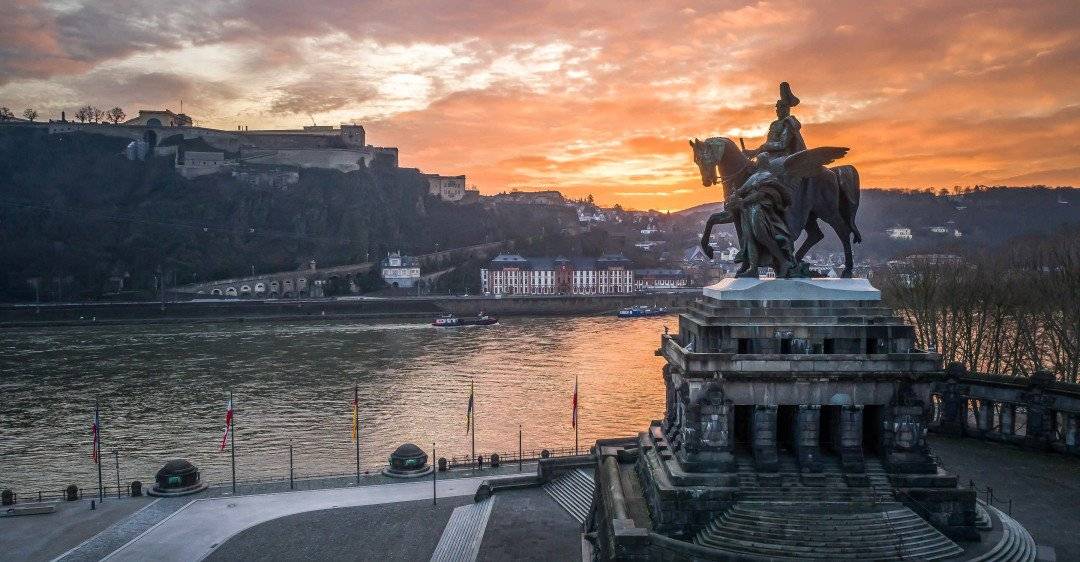 Panoramablick auf Fluss mit bebauten Hügeln und historischem Denkmal im rechten Vordergrund